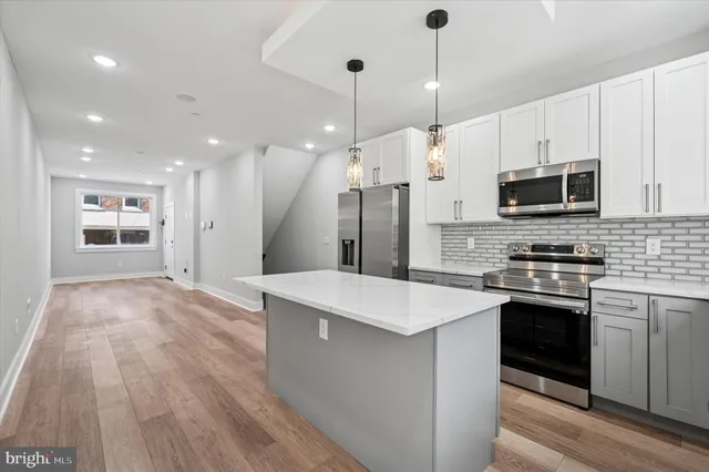 a large kitchen with stainless steel appliances granite countertop a stove a sink and a refrigerator