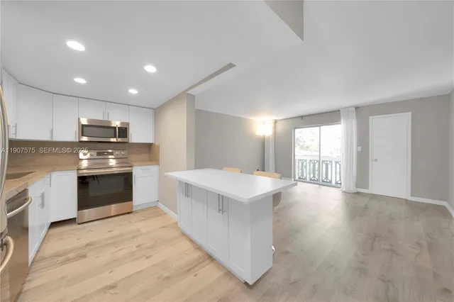 a large kitchen with stainless steel appliances granite countertop a stove a sink and a refrigerator