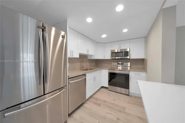 a large kitchen with stainless steel appliances granite countertop a refrigerator and a stove top oven