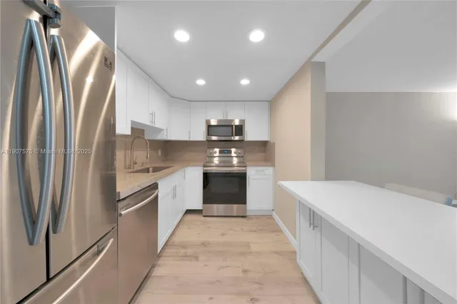 a large kitchen with a large counter top stainless steel appliances and cabinets