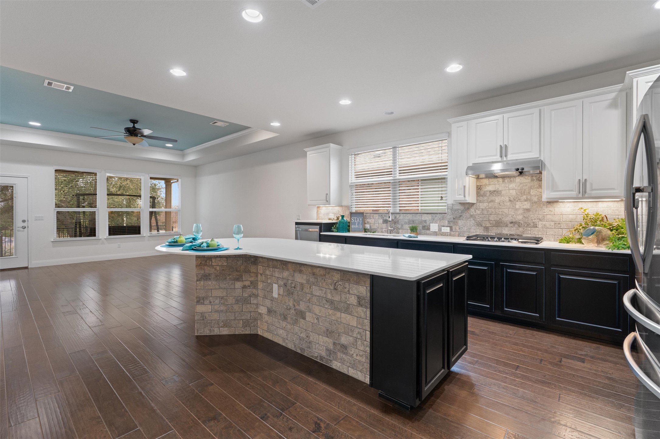 a kitchen with stainless steel appliances granite countertop a stove a sink dishwasher and a large refrigerator with wooden floor