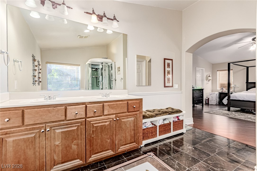135 Broken Putter Way Las Vegas, NV 89148 - Photo 19 of 40 Ensuite bathroom with double vanity, a ceiling fan, dark marble finish floors, wainscoting, and vaulted ceiling