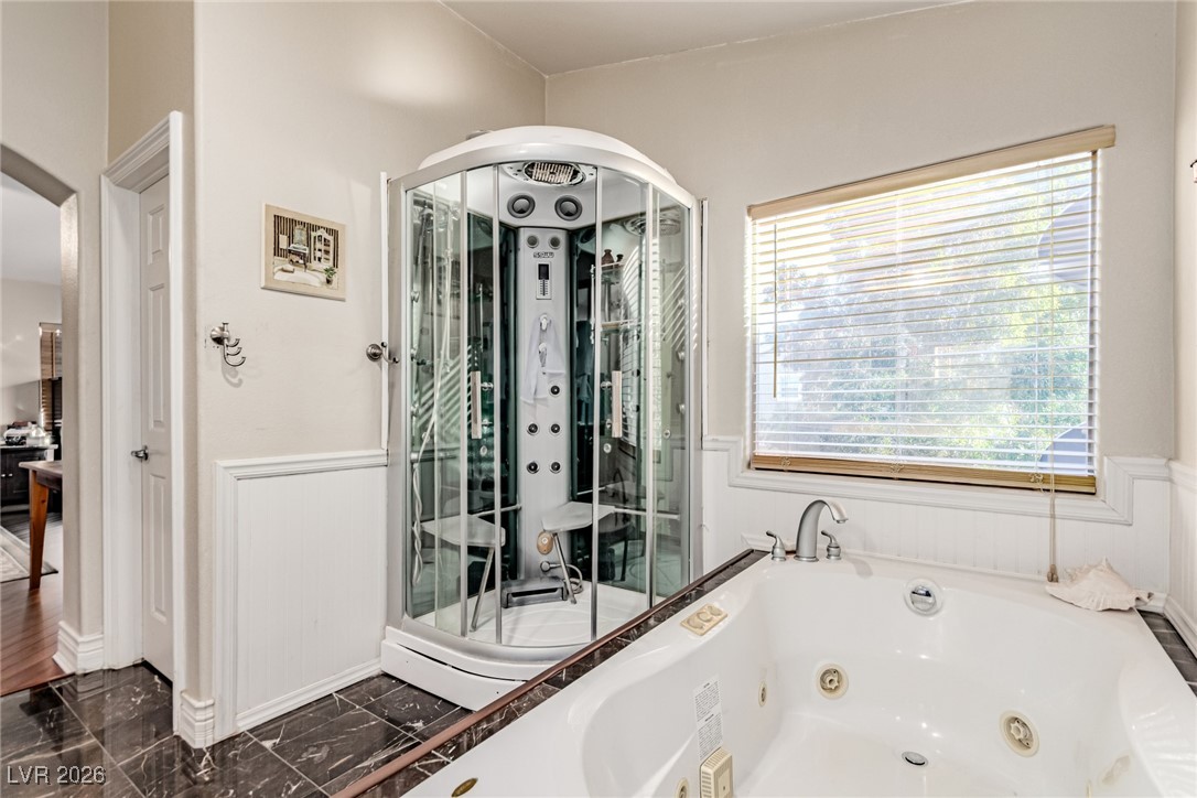 135 Broken Putter Way Las Vegas, NV 89148 - Photo 20 of 40 Bathroom with dark marble finish floors, a jetted tub, and a wainscoted wall