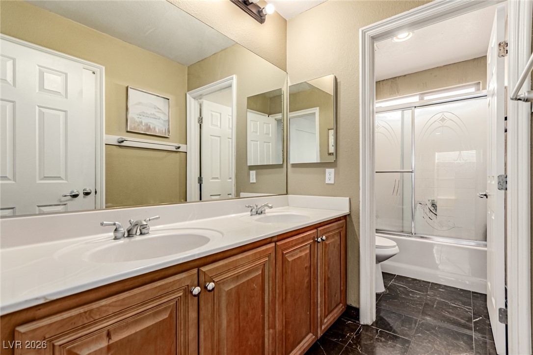 135 Broken Putter Way Las Vegas, NV 89148 - Photo 24 of 40 Bathroom with double vanity, shower / bath combination with glass door, and dark marble finish flooring