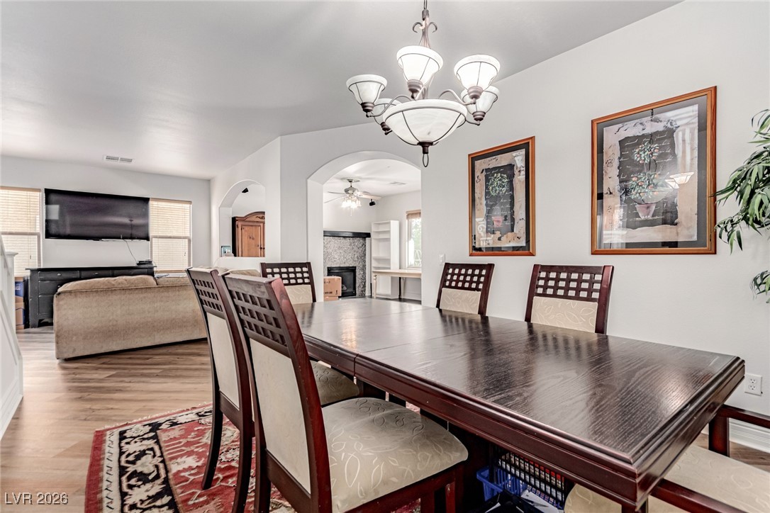 135 Broken Putter Way Las Vegas, NV 89148 - Photo 10 of 40 Dining room with a tile fireplace, arched walkways, light wood-style floors, and a chandelier
