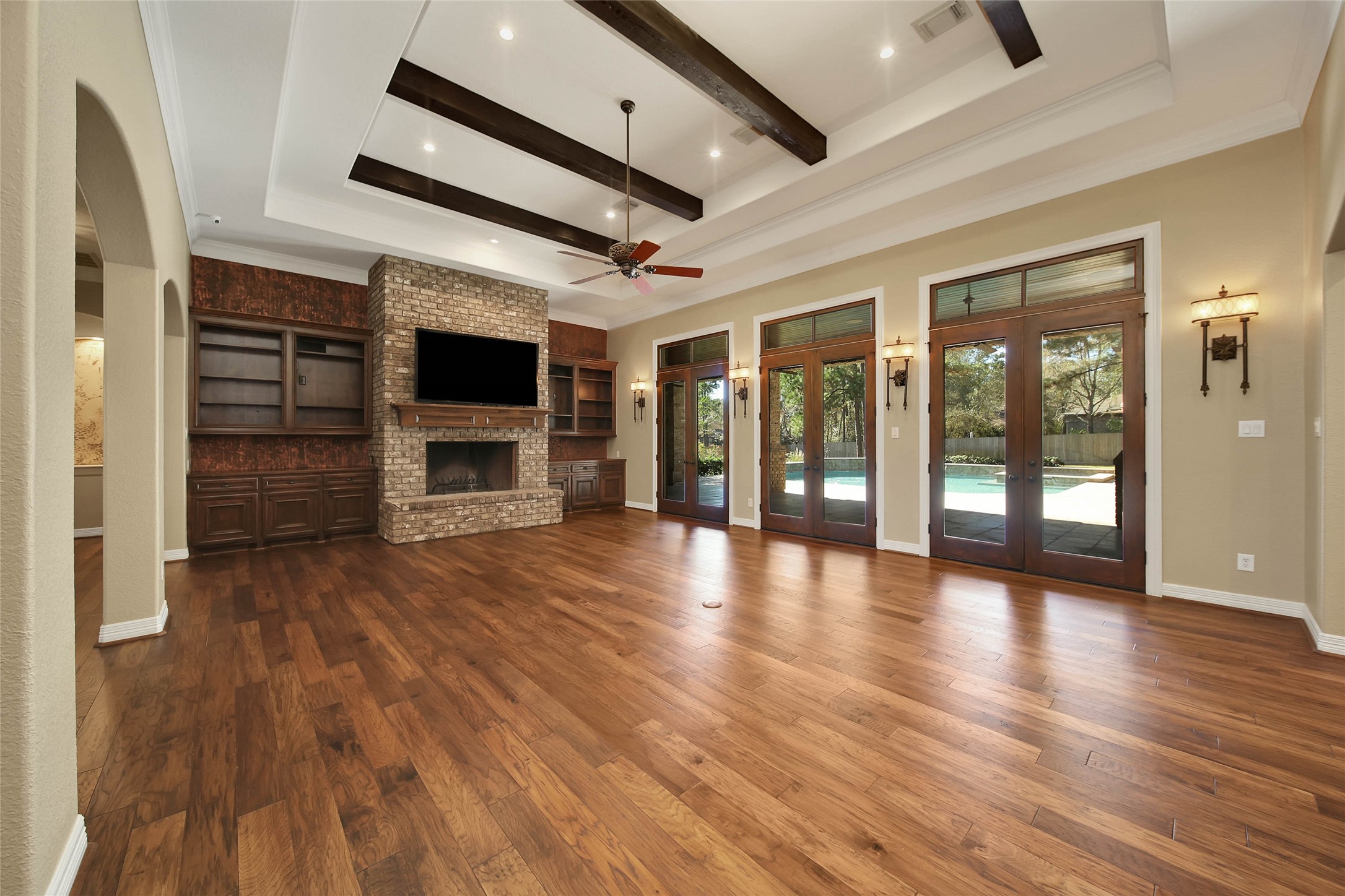 6803 Star Ledge Court Spring, TX 77389 - Photo 9 of 48 The supersized Family Room offers a stately fireplace flanked by built-ins, custom trey ceiling offers recessed lighting and wood beams. sconce lighting, and three sets of French doors leading to the extensive covered outdoor living space - ideal for entertaining.
