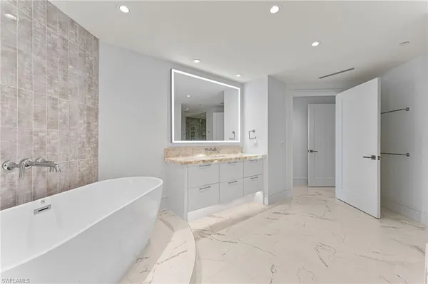 a bathroom with a bathtub sink mirror vanity and toilet