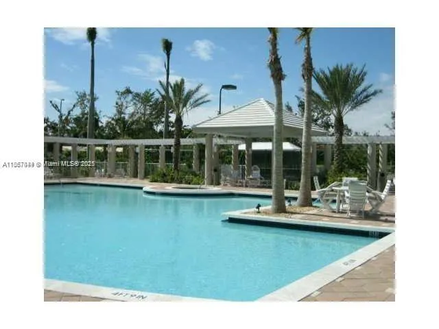 a view of a swimming pool with a lawn chairs under an umbrella