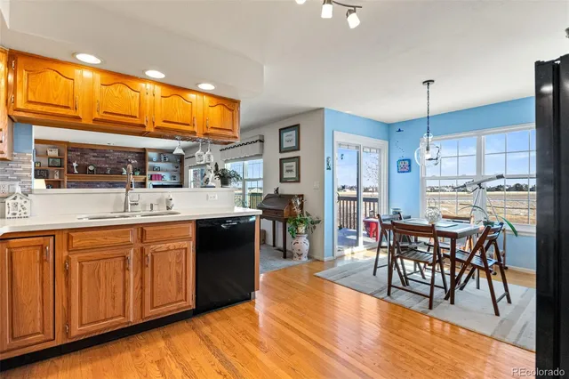 a large kitchen with stainless steel appliances a refrigerator a stove a dining table and chairs with wooden floor