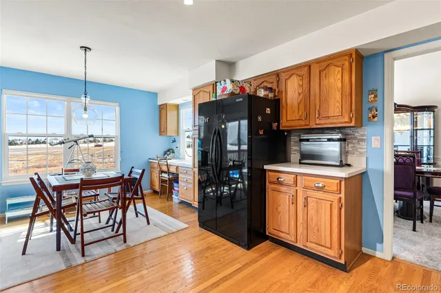 a kitchen with stainless steel appliances granite countertop a refrigerator a stove top oven and a dining table with wooden floor