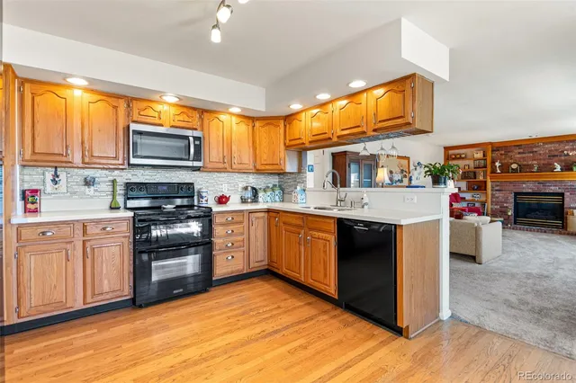 a kitchen with stainless steel appliances granite countertop a stove top oven a sink dishwasher and a microwave oven with large wooden cabinets