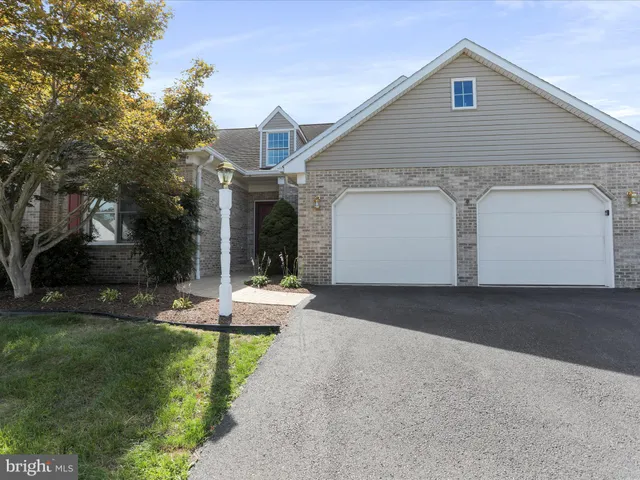 a view of a white house next to a yard and road