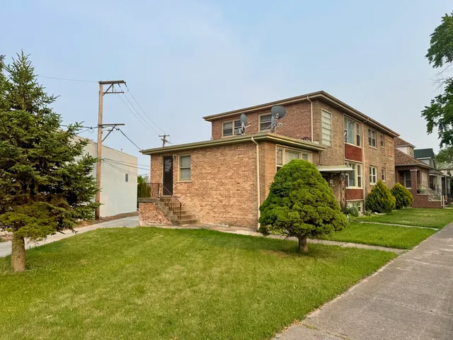 a front view of a house with a yard and trees