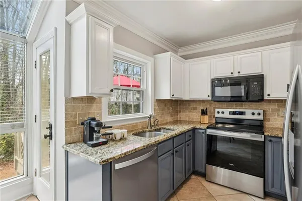 a kitchen with granite countertop a sink stove top oven and microwave