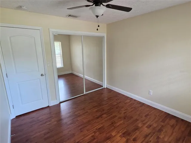 an empty room with wooden floor cabinet and windows