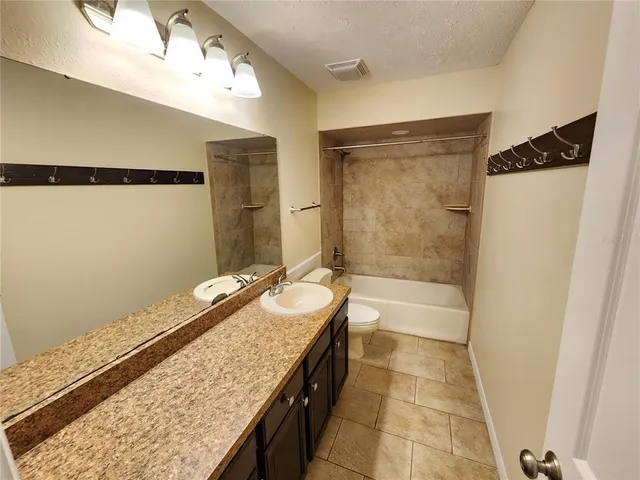 a bathroom with a granite countertop sink a mirror and a bathtub