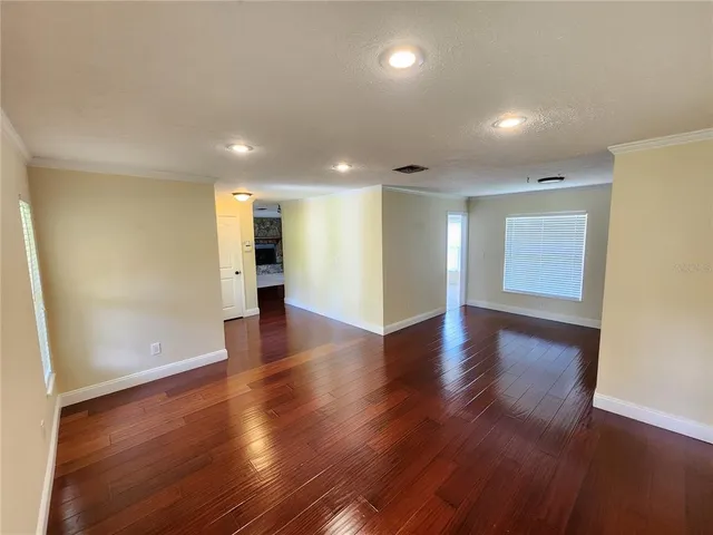 a view of an empty room with wooden floor and windows
