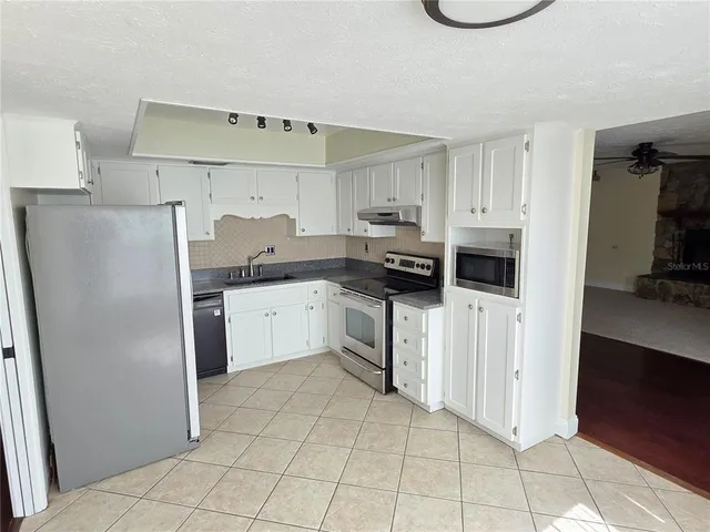 a kitchen with white cabinets a counter top space and stainless steel appliances