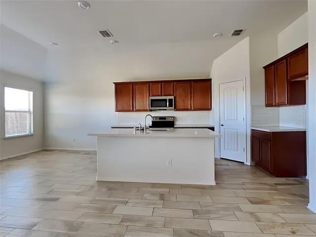 a view of kitchen with granite countertop stove top oven and cabinets