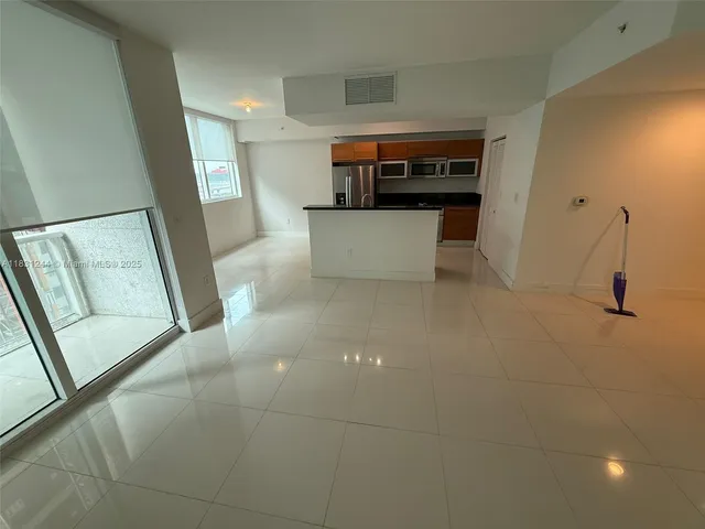 a view of kitchen and empty room with wooden floor