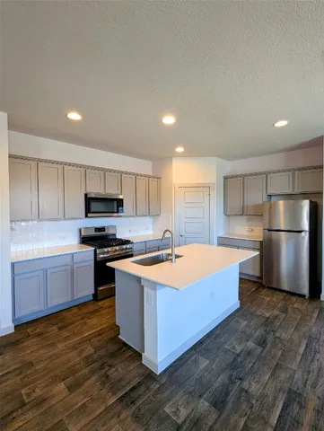 a kitchen with stainless steel appliances a stove a sink a refrigerator white cabinets and a microwave