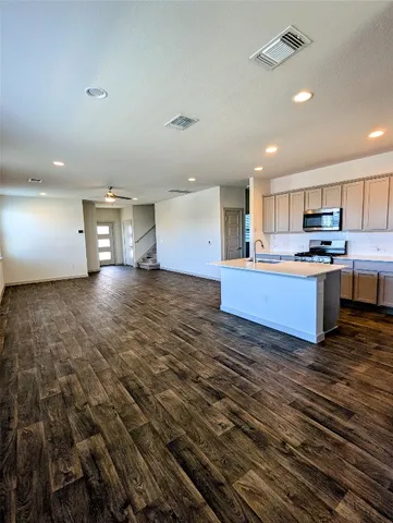 a view of a kitchen with kitchen island wooden floors stainless steel appliances cabinets and a couch