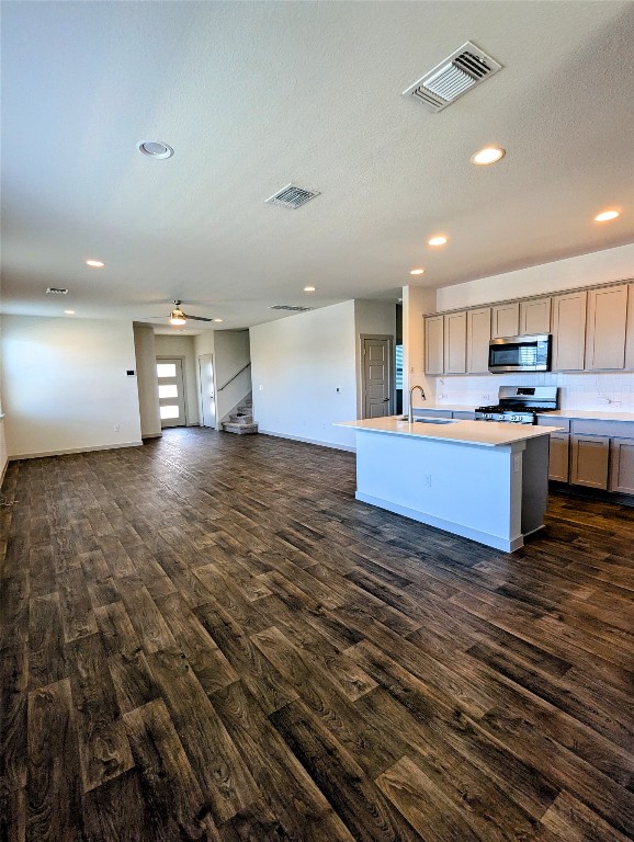 4712 Oxgang Drive Pflugerville, TX 78660 - Photo 5 of 33 a view of a kitchen with kitchen island wooden floors stainless steel appliances cabinets and a couch