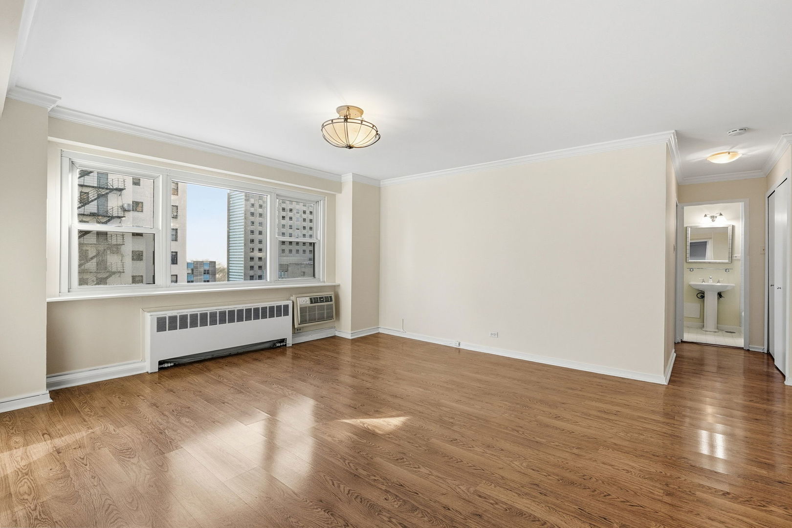 2909 North Sheridan Road, Unit 802 Chicago, IL 60657 - Photo 6 of 22 a view of an empty room with a window and wooden floor