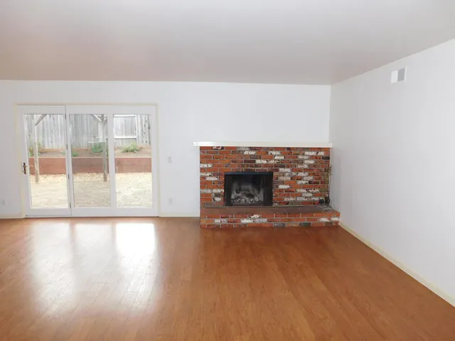 a view of empty room with wooden floor and fireplace