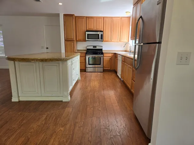 a kitchen with stainless steel appliances granite countertop a refrigerator and a stove top oven