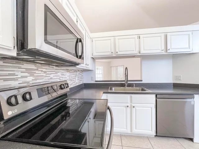 a kitchen with granite countertop a stove sink and cabinets