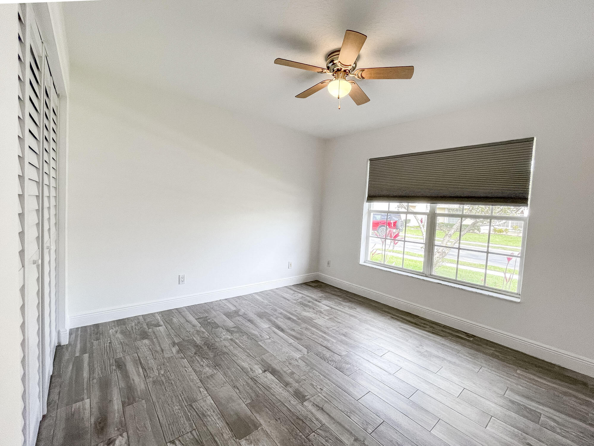 252 Moccasin Trail West Jupiter, FL 33458 - Photo 17 of 24 an empty room with wooden floor fan and windows