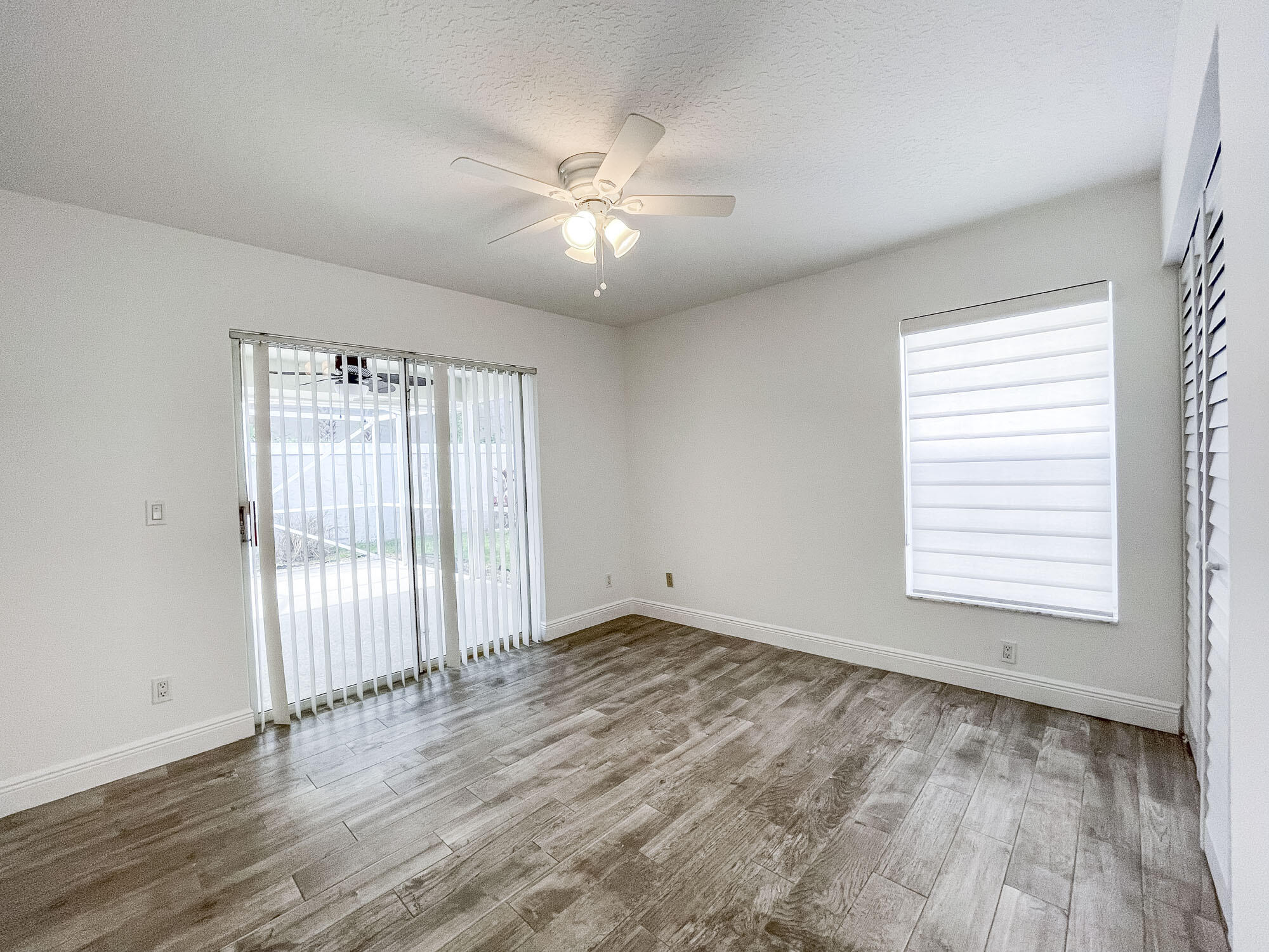 252 Moccasin Trail West Jupiter, FL 33458 - Photo 18 of 24 an empty room with wooden floor fan and windows