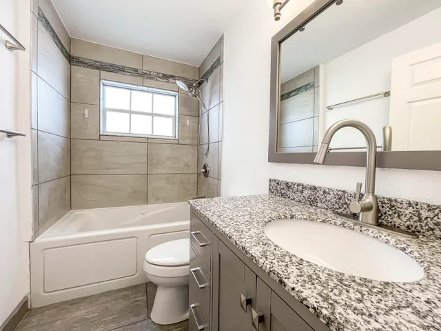 a bathroom with a granite countertop sink a toilet and bathtub