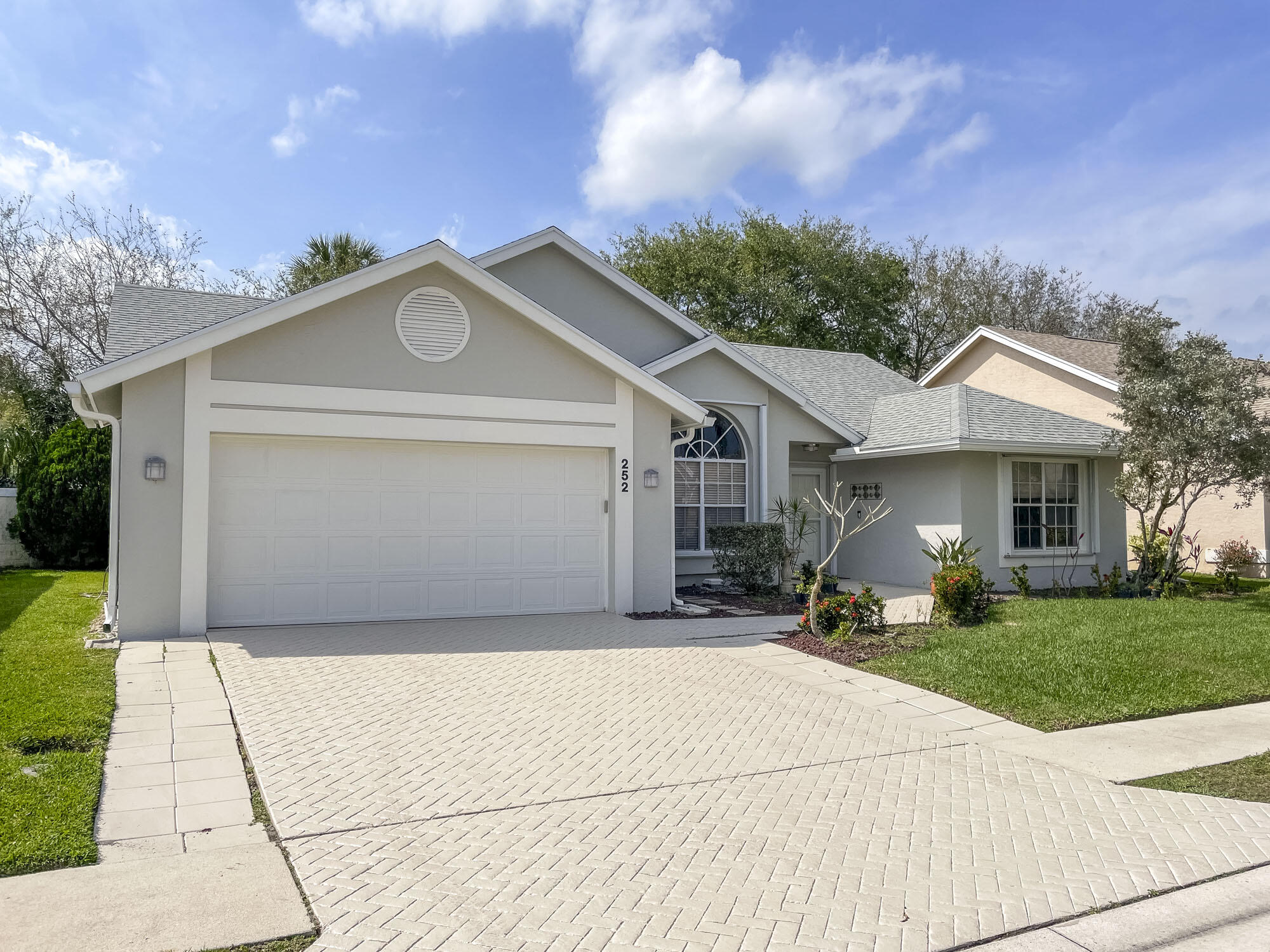 252 Moccasin Trail West Jupiter, FL 33458 - Photo 23 of 24 a front view of a house with a garden and trees