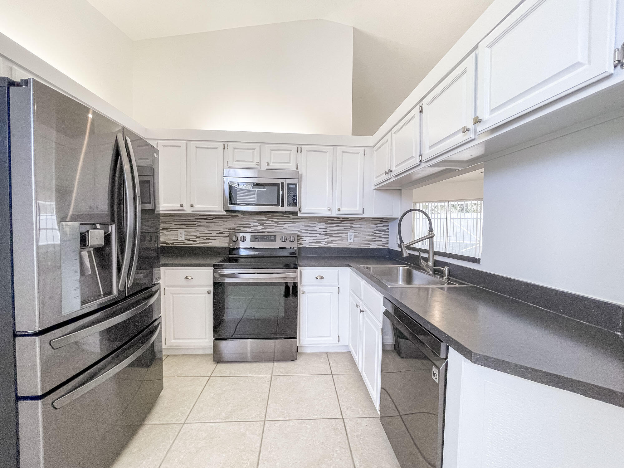 252 Moccasin Trail West Jupiter, FL 33458 - Photo 10 of 24 a kitchen with kitchen island granite countertop a sink appliances cabinets and counter space