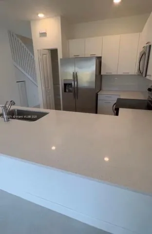 a view of a refrigerator in kitchen and a sink