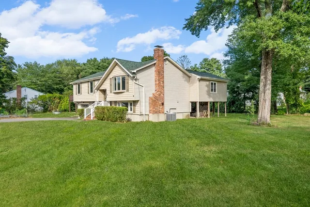 a view of a house with a big yard and large trees