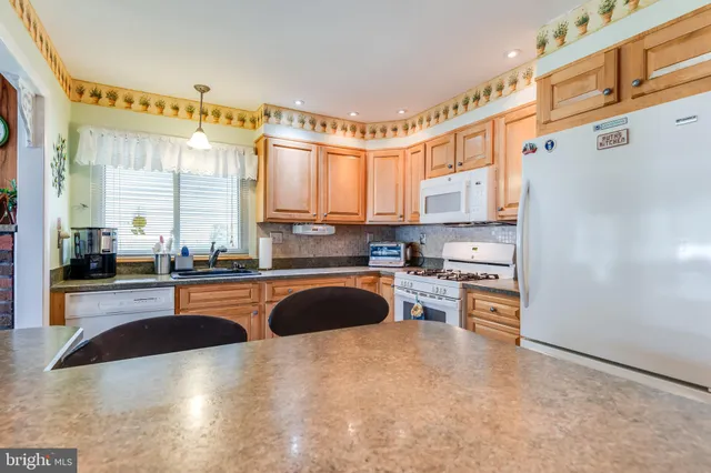 a kitchen with stainless steel appliances granite countertop a sink a stove and a refrigerator with wooden floor