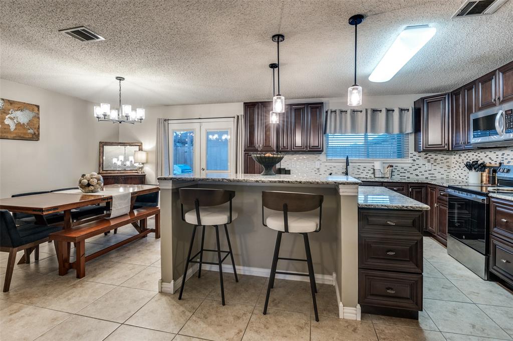 656 Condor Trail Saginaw, TX 76131 - Photo 9 of 25 a kitchen with kitchen island granite countertop a sink a counter and chairs in it