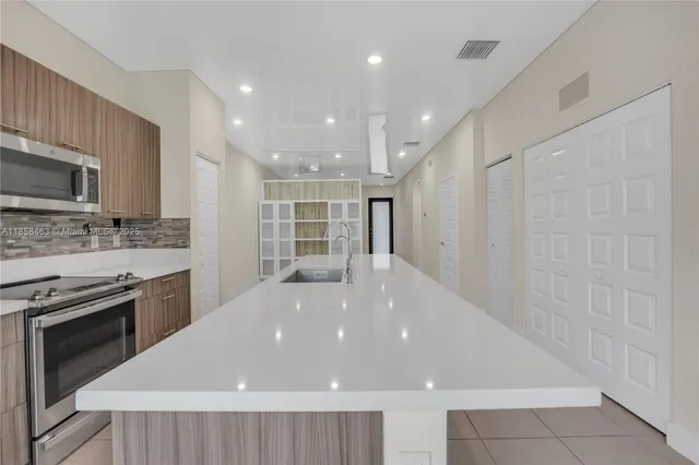 a large kitchen with a stove a sink and a microwave