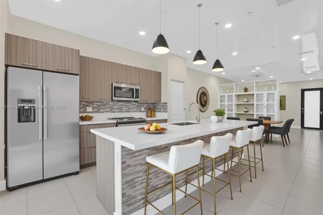 a kitchen with stainless steel appliances kitchen island granite countertop a table chairs and a refrigerator