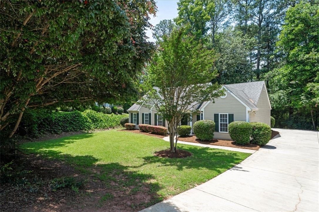 212 Blue Ridge Drive Clemson, SC 29631 - Photo 2 of 33 A traditional home with light siding and dark shutters nestled among mature trees and vibrant landscaping.