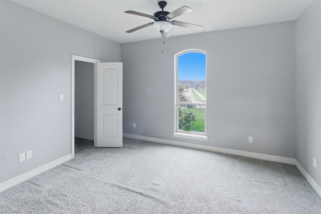 7765 Hickory Spring Lane Tyler, TX 75703 - Photo 27 of 38 Carpeted room featuring light gray walls, a ceiling fan with light fixture, and an arched window