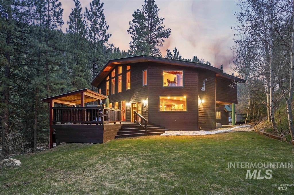 224 Dakota Road Mountain Home, ID 83647 - Photo 1 of 50 Dark wood-sided residence featuring a multi-level deck with a covered portion, a sloped green lawn, and substantial windows