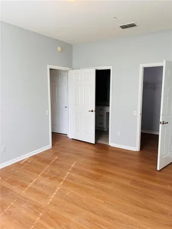 a view of an empty room with wooden floor and closet