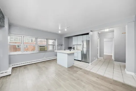 a large white kitchen with a refrigerator a sink dishwasher and a large window