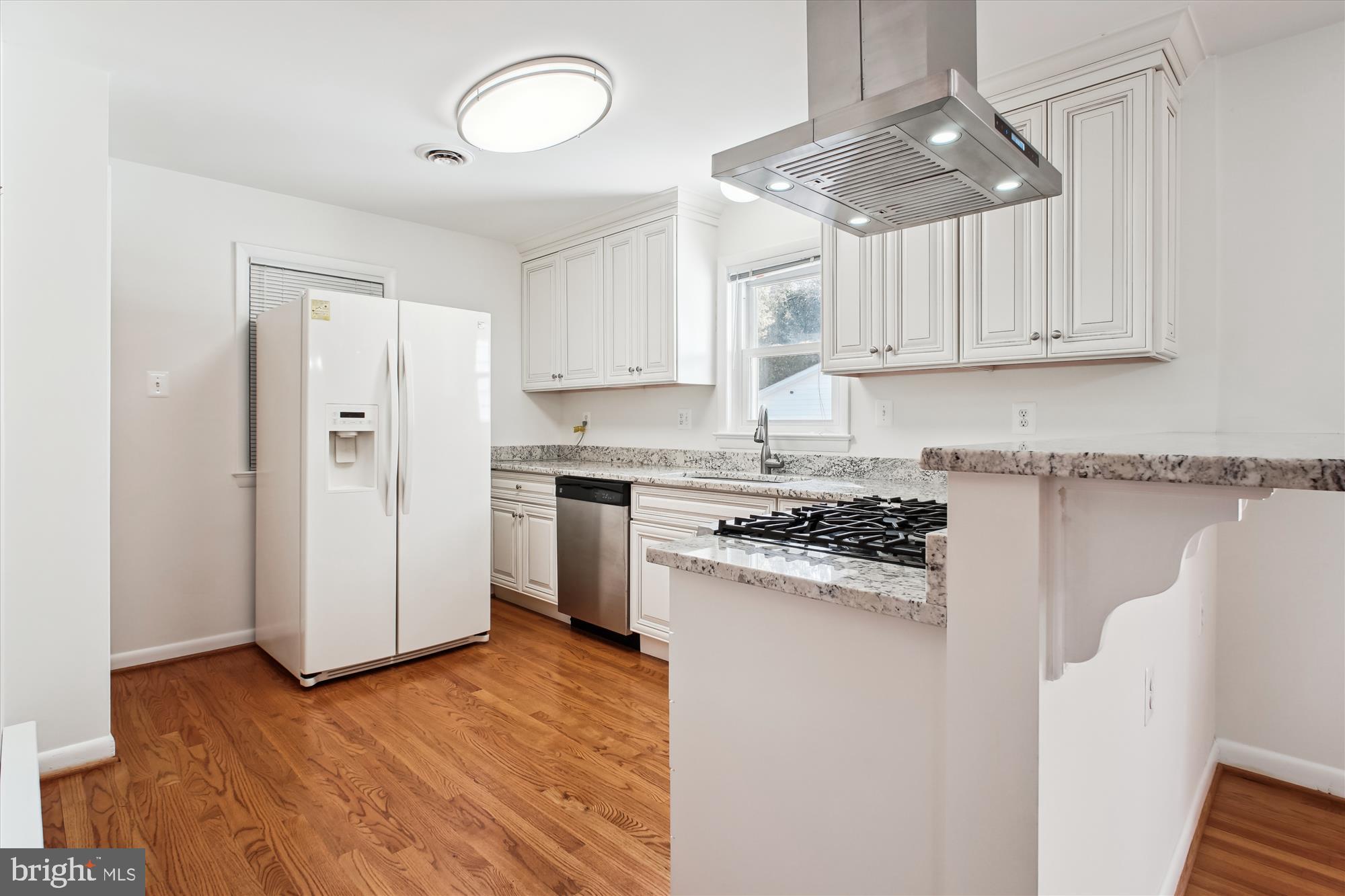 10607 Judicial Drive Fairfax, VA 22030 - Photo 20 of 60 a kitchen with granite countertop a refrigerator a stove a sink and white cabinets with wooden floor