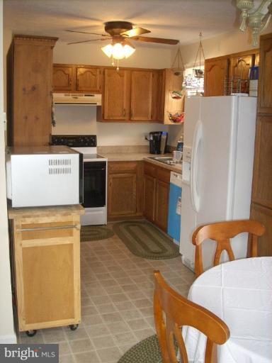 11594 Big Sandy Run Road Lusby, MD 20657 - Photo 6 of 16 a kitchen with stainless steel appliances granite countertop a refrigerator a stove and a sink with wooden floor