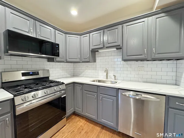 a kitchen with stainless steel appliances a sink dishwasher a stove and microwave